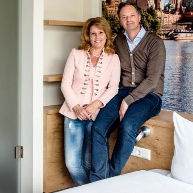 man en vrouw lachend naar camera in hotel kamer