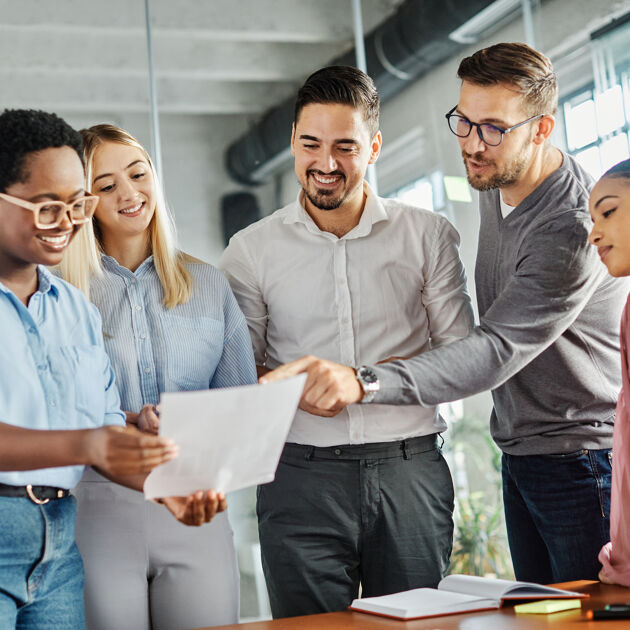 Een groep mensen staat naast een tafel, een man wijs naar een document.