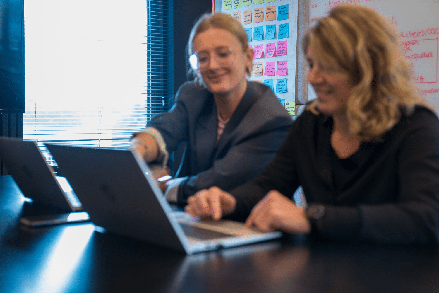 team-marketing Vrouw laat iets zien op computer scherm aan andere vrouw. Ze zijn wazig