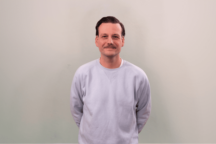 medewerker Qredits Tim Bouman grijze trui snor
