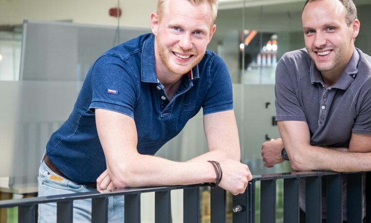 Twee mannen hangen over reling