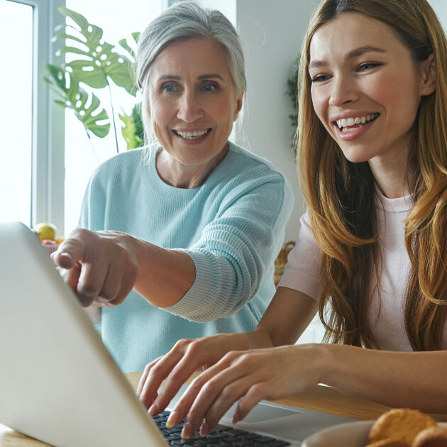 Twee vrouwen kijken naar een laptop, één vrouw typt en één vrouw wijst ernaar. 