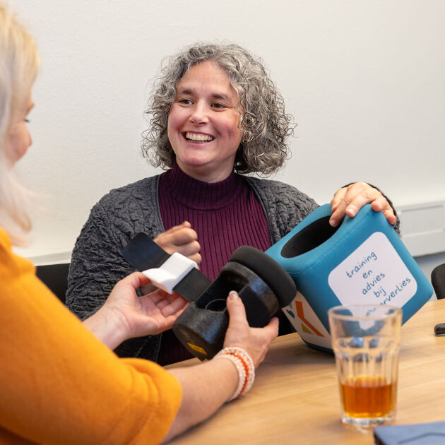 Vrouw in rood shirt laat iets zien aan vrouw in geel shirt