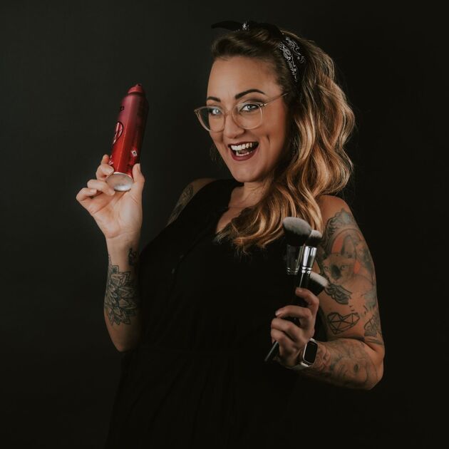 Vrouw met bril en spuitbus in de handen voor een zwarte achtergrond. 