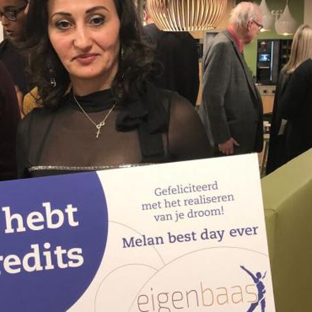 Vrouw staat met certificaat van Qredits van het Eigenbaas migranten programma
