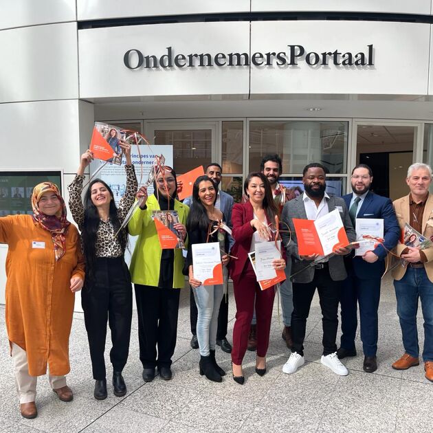 Een blije groep met mensen met een diploma en een roos. 