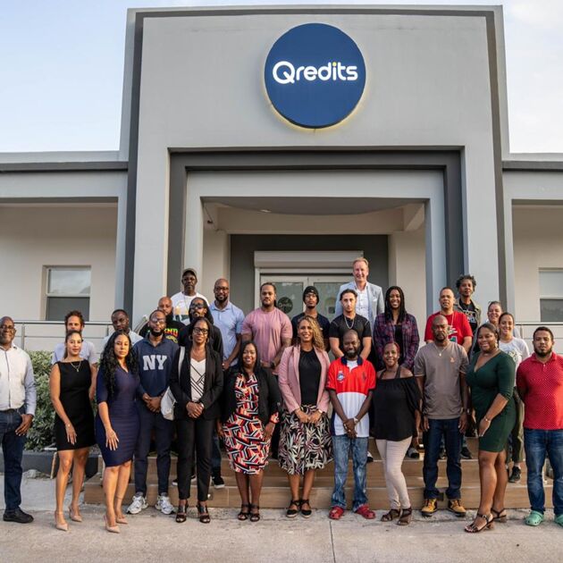 Een groep mensen op een trap voor een pand van Qredits. 