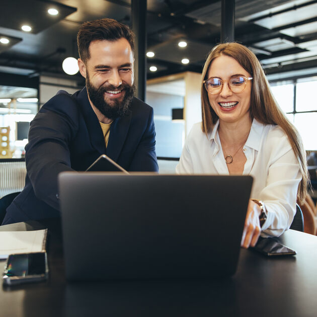 Man en vrouw zitten, vrouw wijst naar laptop.