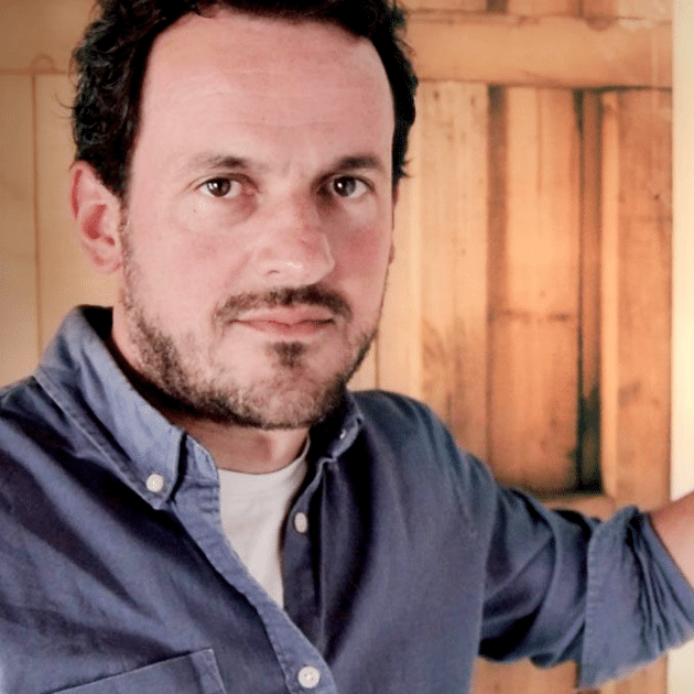 Man in blauw shirt voor houten muur
