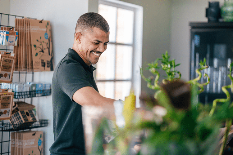 man-lacht-en-staat-bij-plant