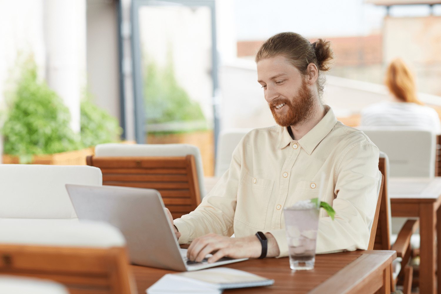 Man in licht shirt zit aan een tafel en werkt op een laptop