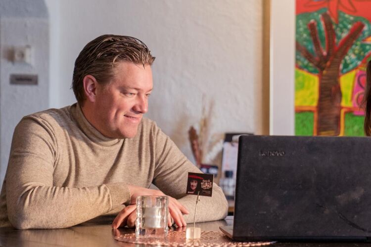 Man en vrouw zitten aan een tafel en kijken naar een laptopscherm.