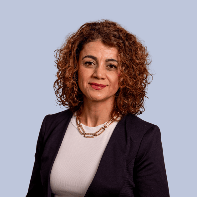 medewerker Qredits Nouna Hamazasip vrouw in wit jasje voor grijze achtergrond