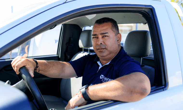 Man in blauw shirt zit in auto met raam omlaag