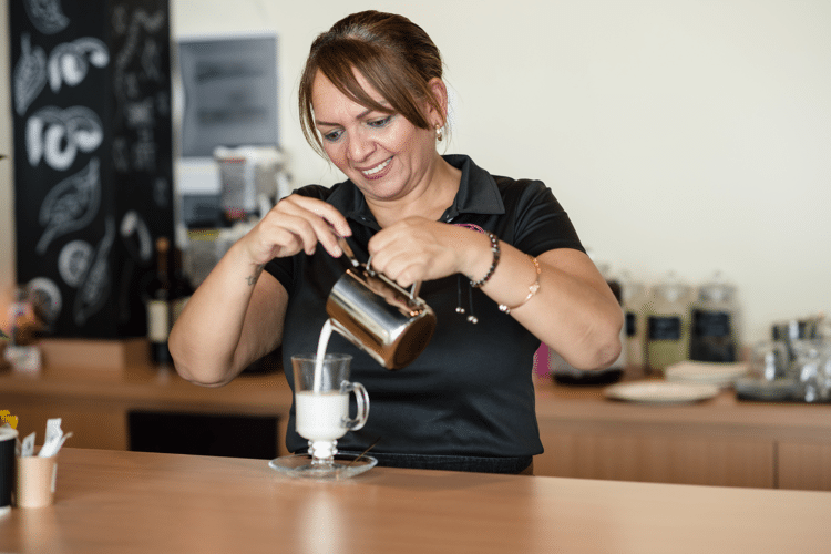 Lachende vrouw in zwart shirt schenkt drinken in glas