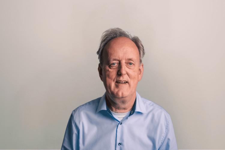 Oscar medewerker Qredits man in blauw shirt voor grijze achtergrond