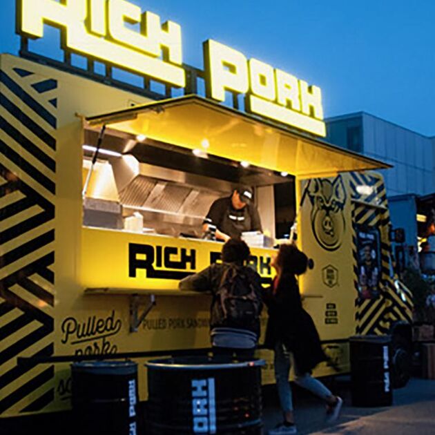 Man staat in zijn foodtruck en helpt 2 vrouwelijke klanten