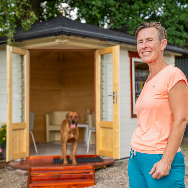 Service_Honden_Ostheopaat_staat_buitne_voor_tuinhuis_met_hond