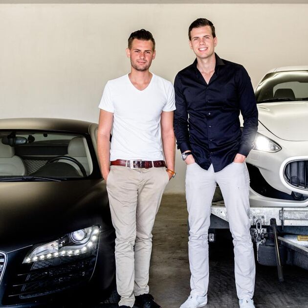 Twee mannen staan voor 2 sportauto's 