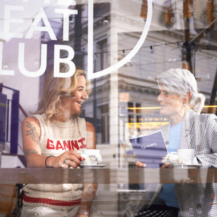 Twee vrouwen zitten samen achter glas