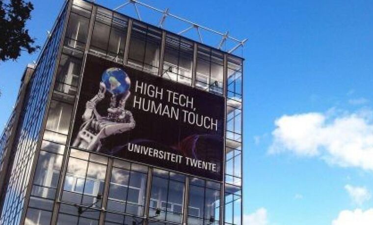 Gebouw van de Universiteit Twente met poster en blauwe lucht