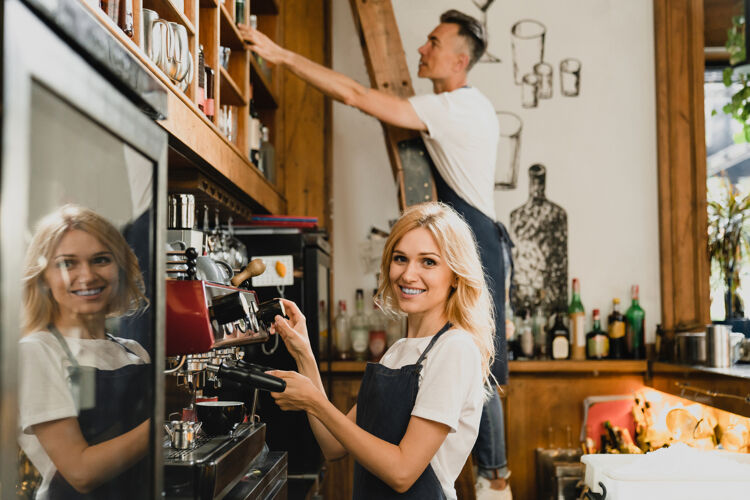 vrouw-bezig-met-koffiezetapparaat-man-in-de-achtergrond