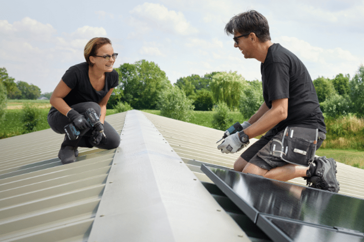 Man en vrouw leggen zonnepanelen neer op en dak