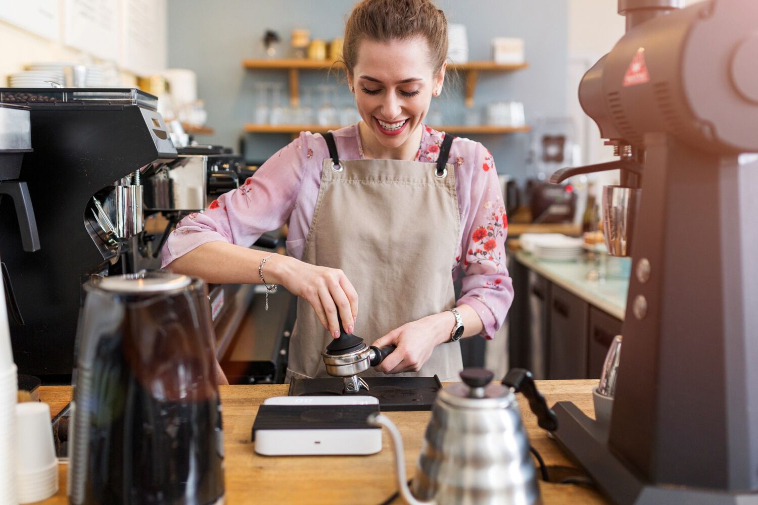 Lachende vrouw met schort om maak koffie.