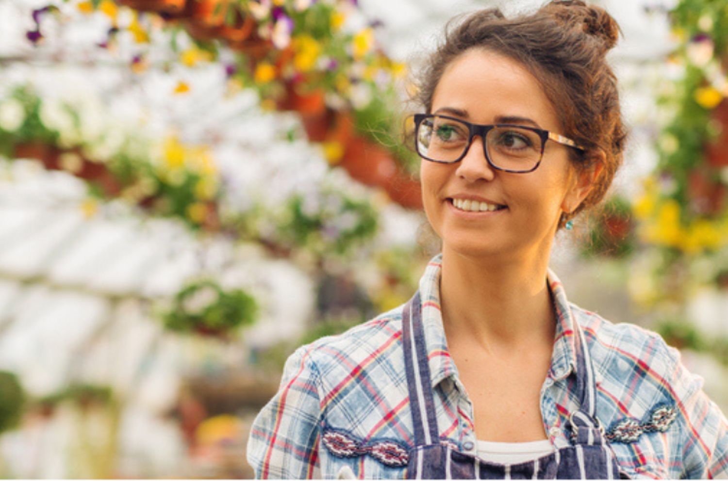 Header van een vrouw die in een kas met bloemen staat