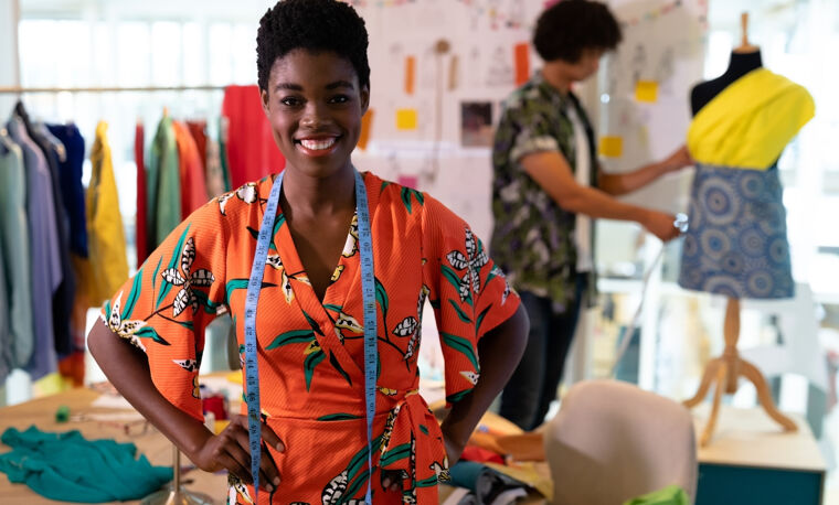Een vrouw staat trots in haar gefinancierde kledingzaak