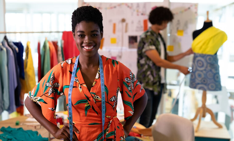Een vrouw staat trots in haar gefinancierde kledingzaak