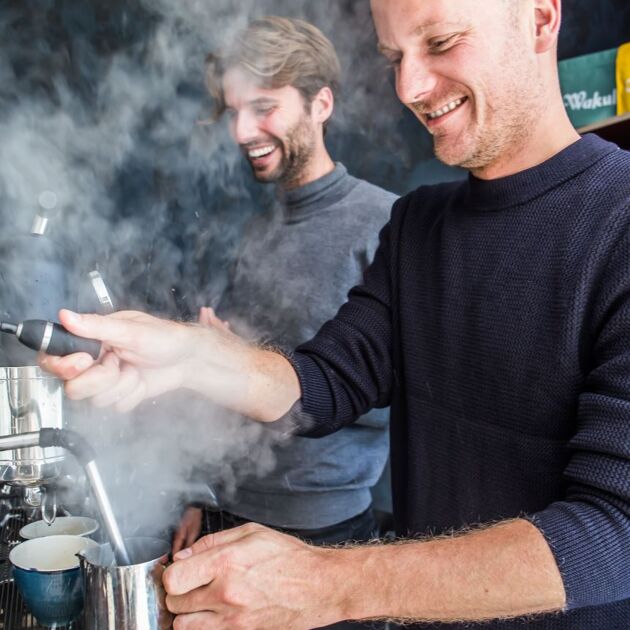 Twee mannen in donkere shirt zetten koffie met een lach