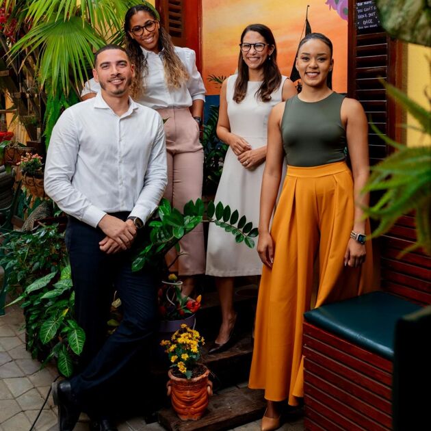 Vier werknemers van Qredits Aruba met veel planten