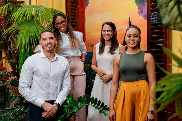 Vier werknemers van Qredits Aruba met veel planten