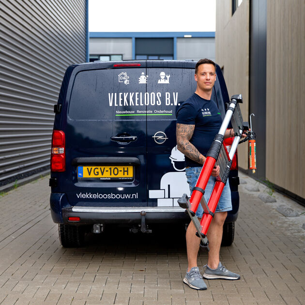 Man staat met een ladder in zijn hand voor een bus