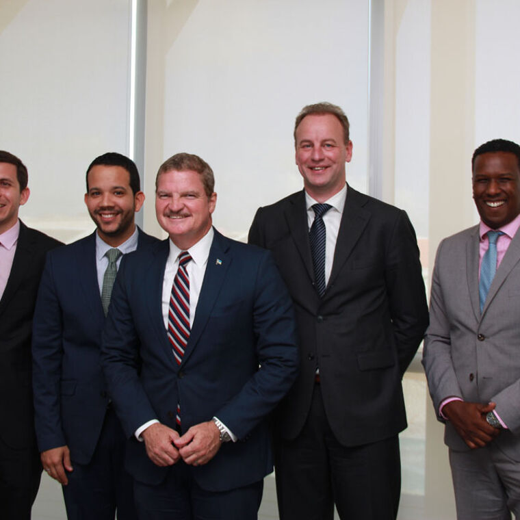 Een groep van 5 mannen in pak staan in een witte ruimte