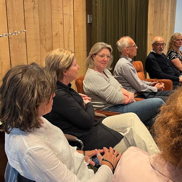 Een groep mensen zitten in een rij naast elkaar.