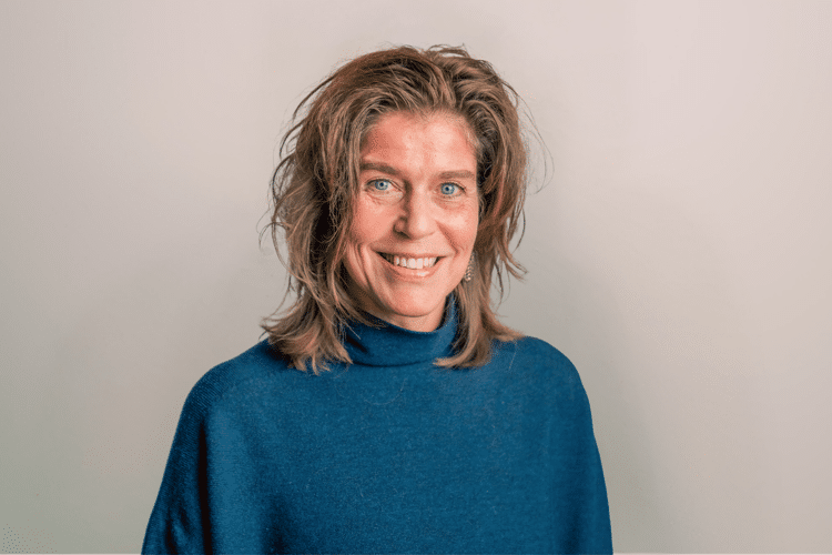 medewerker Qredits José van der Looij vrouw in blauw shirt voor grijze achtergrond