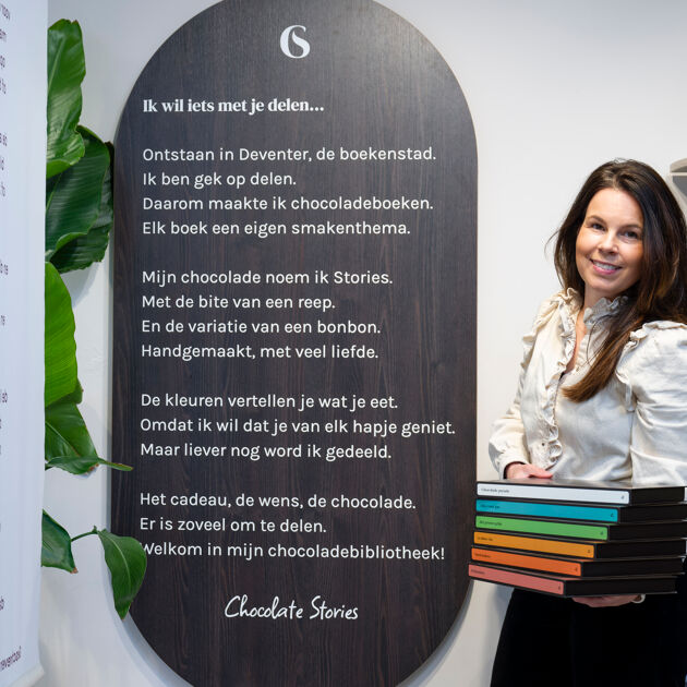 Vrouw kijkt lachend en staat met chocoladeboeken in haar handen. 