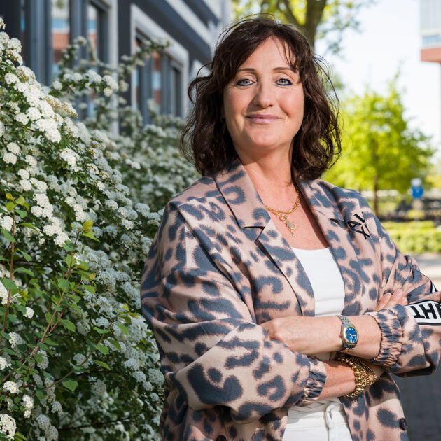 Vrouw staat trots voor bosjes.