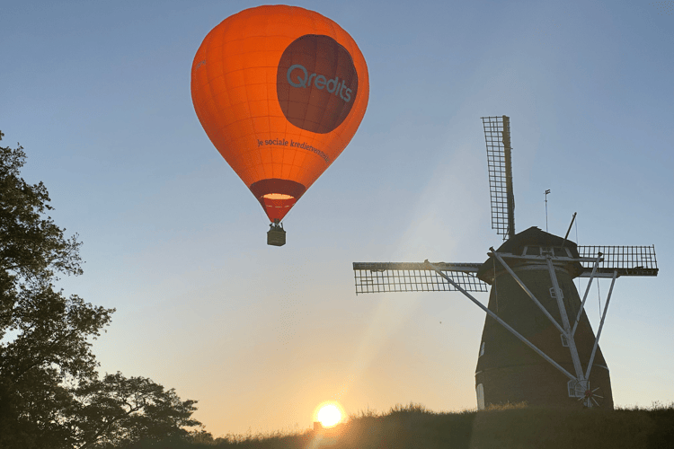Een luchtballon van Qredits vliegt naast een molen