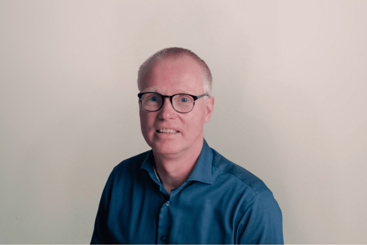 Jeroen medewerker Qredits man in blauw shirt voor grijze achtergrond