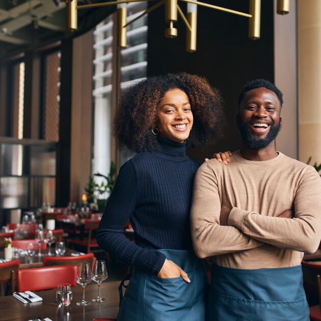 Man en vrouw lachen naar camera in restaurant