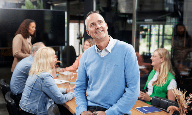 Man in blauw shirt zit op tafel en kijkt dromerig 