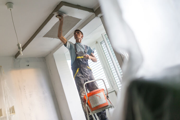 man-in-overall-op-ladder-aan-het-stuken
