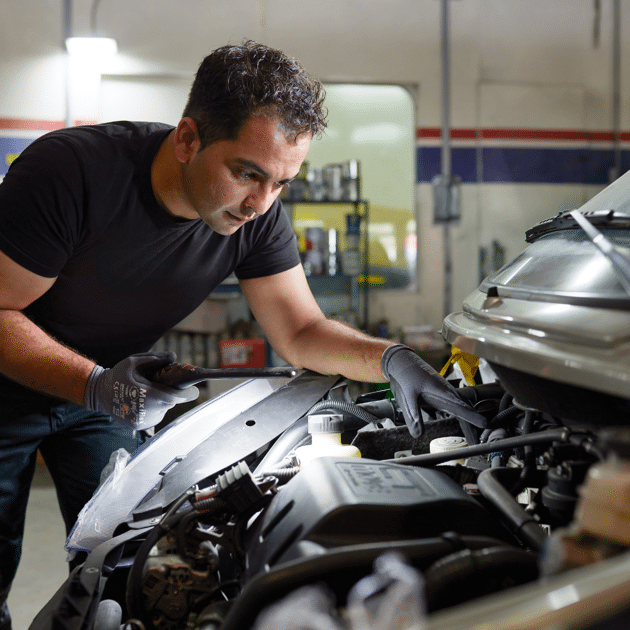 Man in zwart shirt en handschoenen werkt aan een auto