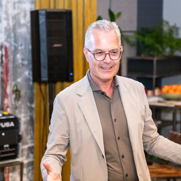 Een man met een bril in een licht jasje is iets aan het vertellen