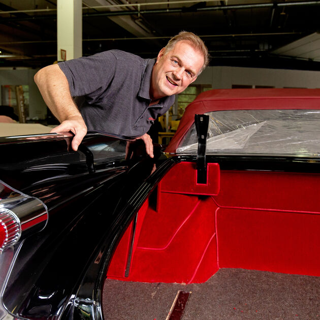 Man werkt aan een rode auto in een garage