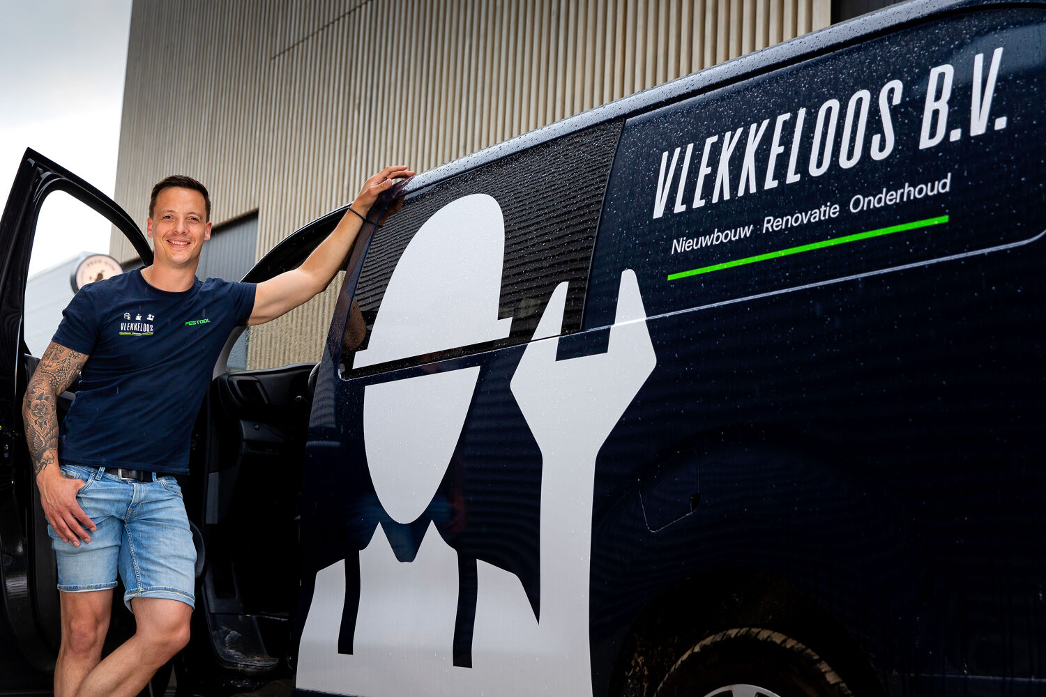 Man leunt tegen een bus van Vlekkeloos BV aan.