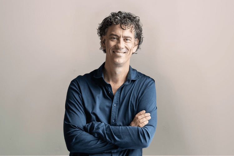 Man-met-baluwe-blouse-voor-grijze-wand